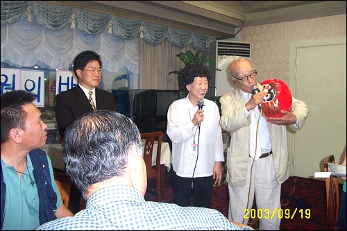 "이 오뚜기처럼, 평택분들도 아무리 어렵고 힘든 일이 닥쳐도 또 일어서고, 또 일어서서 끝내 승리하시길 바랍니다. 여기 이 두 눈은 그려넣지 않았습니다. 한 눈은 투쟁하시는 분들의 의지를 담아 그려 넣으시고, 다른 한 눈은 투쟁을 승리로 이끄신 뒤에 그려 넣어 완성해 주십시오!" 간곡한 인사말과 함께 오뚜기를 선물하는 기쿠치 단장 